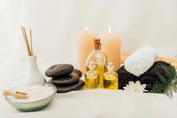 Close up view of arrangement of spa treatment accessories with towels, pebbles and essential oil on white background — Stock Photo