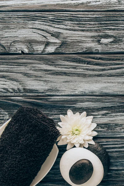 Disposición plana con spa y tratamiento de masaje con toalla, guijarros y flor de crisantemo sobre fondo de madera - foto de stock