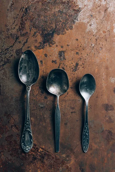 Elevated view of three silver spoons on grungy table — Stock Photo