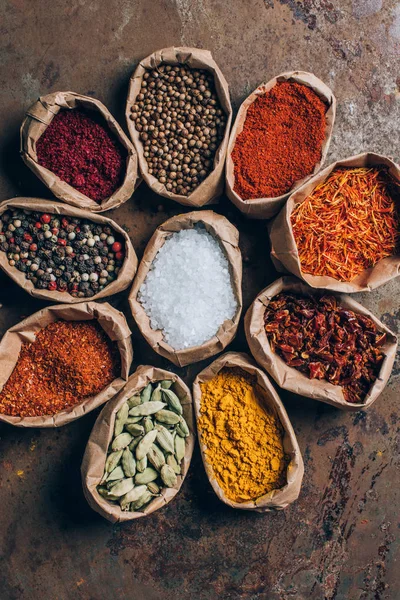 Top view of coriander, saffron and chilli flakes in paper bags on table — Stock Photo