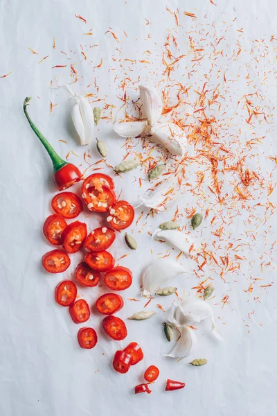 Verstreuter Knoblauch, Gewürze und geschnittene Chilischoten auf weißem Tisch — Stockfoto