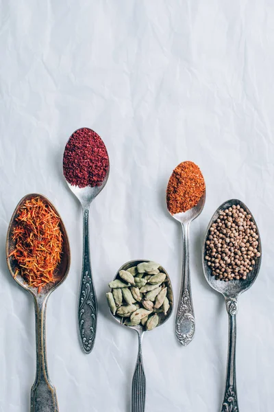 Elevated view of different spices in spoons on white table — Stock Photo