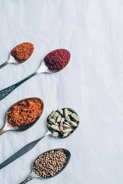 Top view of dry spices in spoons on white table — Stock Photo