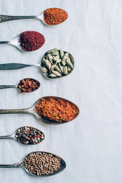 Top view of colorful spices in spoons on white table — Stock Photo