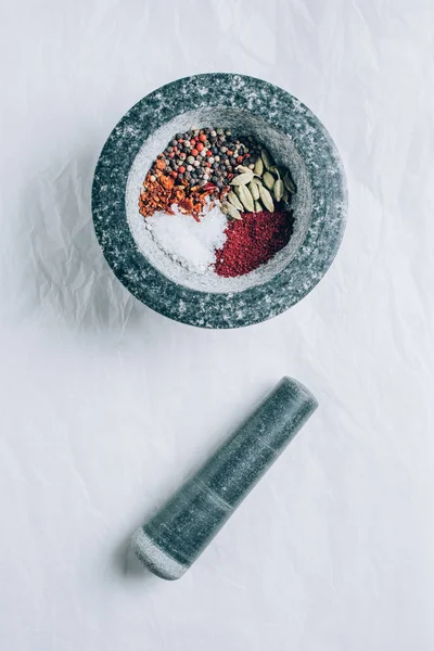 Erhöhte Ansicht des Mörsers mit Gewürzen und Stößel auf weißem Tisch — Stockfoto