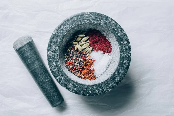 Vue de dessus du mortier avec épices et pilon sur table blanche — Photo de stock