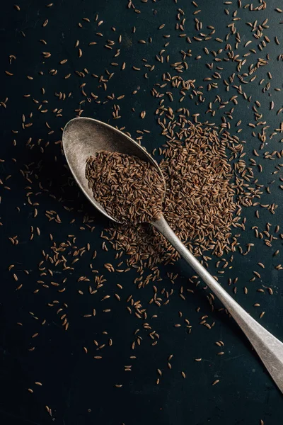 Vue du dessus du cumin sur cuillère et table sombre — Photo de stock