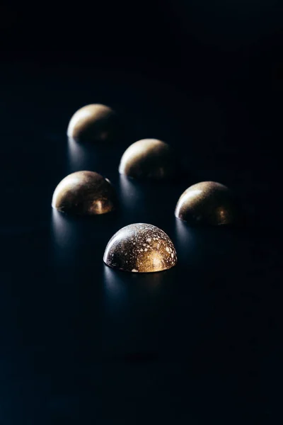 Vista de cerca de caramelos de chocolate colocados en fila sobre fondo negro - foto de stock