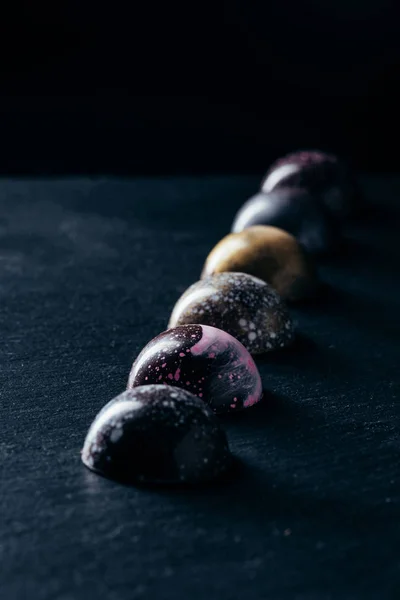 Caramelle al cioccolato poste in fila su sfondo nero — Foto stock