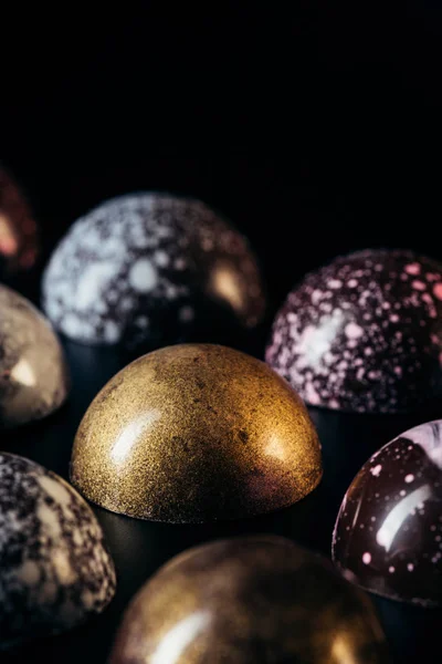 Vista da vicino di mucchio di diverse caramelle al cioccolato su sfondo nero — Foto stock