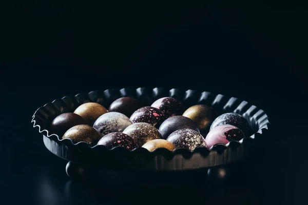 Mucchio di diverse caramelle al cioccolato in ciotola su sfondo nero — Foto stock