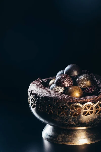 Pile de bonbons au chocolat différents dans un bol vintage sur fond noir — Photo de stock