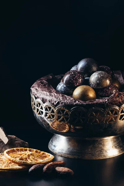 Primo piano vista di noci, fette di arancia secca, caramelle in ciotola vintage e pezzi di cioccolato su sfondo nero — Foto stock