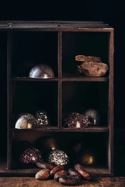 Closeup view of nuts, chocolate pieces and candies on shelves on black background — Stock Photo