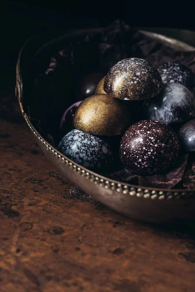 Pile de différents bonbons au chocolat dans un panier en métal sur une table en bois — Photo de stock