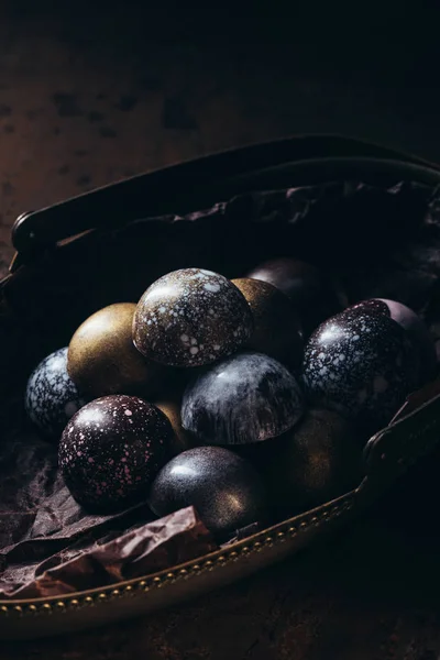 Vista de cerca de la pila de diferentes caramelos de chocolate en la cesta de metal en la mesa de madera - foto de stock