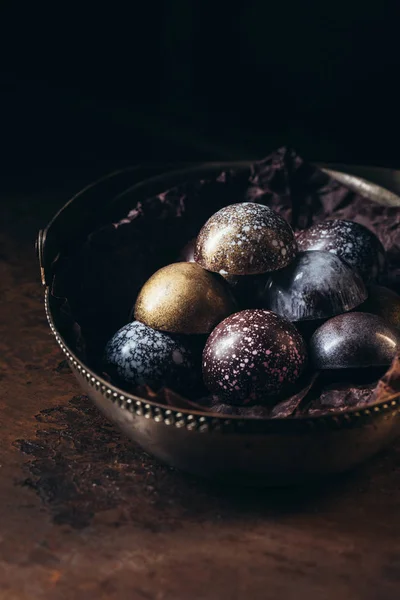 Various chocolate candies in metal basket on black background — Stock Photo