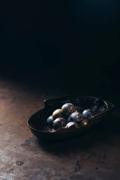 Pile de bonbons au chocolat différents dans le panier en métal sur fond noir — Photo de stock