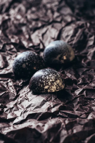 Primo piano di tre caramelle al cioccolato su carta sgualcita — Foto stock