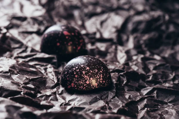 Imagen de cerca de dos caramelos de chocolate con salpicaduras de color rosa sobre papel arrugado - foto de stock