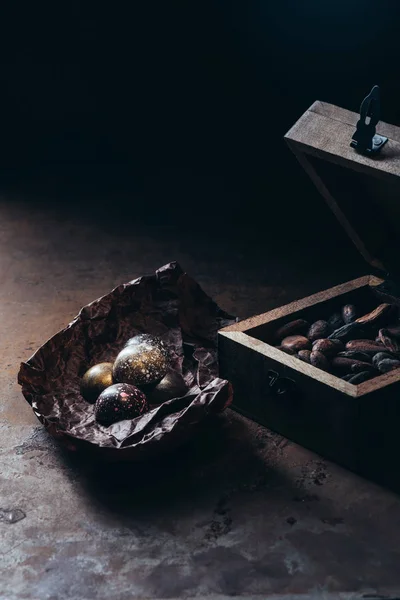 Крупный план деревянной коробки с орехами и шоколадными конфетками на скомканной бумаге — стоковое фото