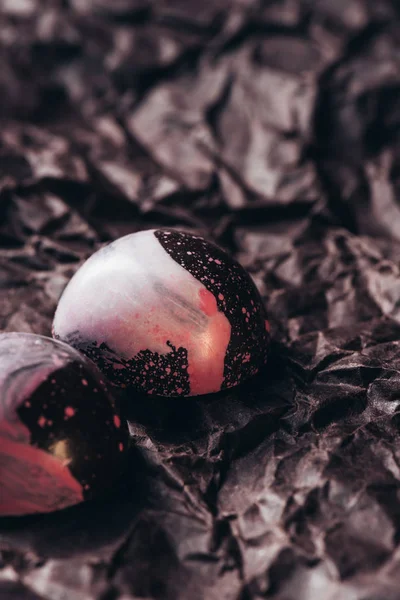 Крупным планом двух шоколадных конфет с розовыми брызгами на скомканной бумаге — стоковое фото