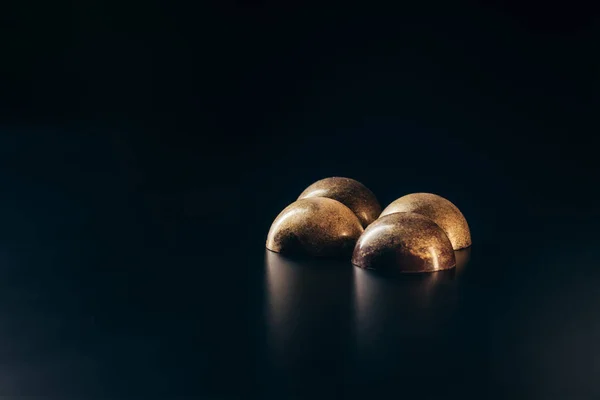 Close up view of of chocolate candies with golden splashes on black background — Stock Photo