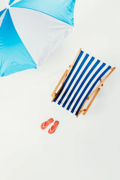 Top view of beach umbrella, striped beach chair and flip flops isolated on white — Stock Photo