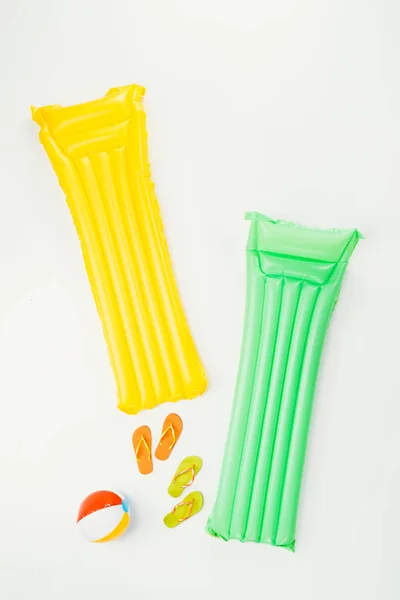 Vue de dessus des matelas de natation, ballon de plage gonflable et tongs isolées sur blanc — Photo de stock