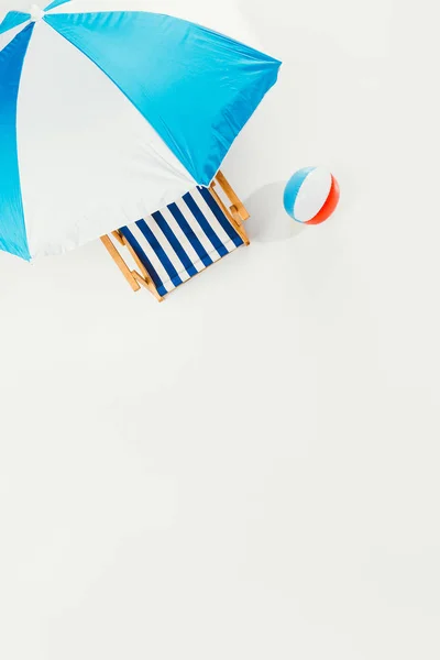 Vista superior de la sombrilla de playa, silla de playa a rayas y bola de playa inflable aislada en blanco - foto de stock