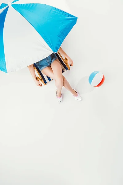 Vue du dessus de la femme assise sur une chaise sous un parasol isolé sur blanc — Photo de stock