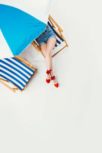 Vista superior de la mujer descansando en silla bajo el paraguas de la playa aislado en blanco — Stock Photo