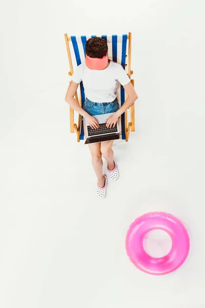 Overhead view of woman sitting in striped beach chair and using laptop isolated on white — Stock Photo