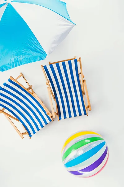 Вид зверху на пляжну парасольку, смугасті пляжні стільці та надувний м'яч ізольовані на білому — стокове фото