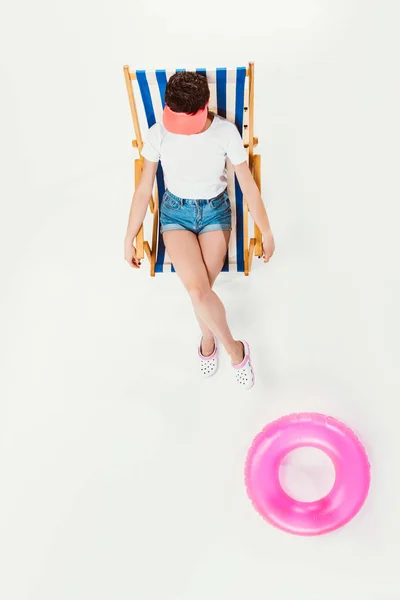 Overhead view of woman sitting in striped beach chair near inflatable ring isolated on white — Stock Photo