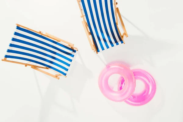 Vista superior de cadeiras de praia listradas e anéis infláveis isolados no branco — Fotografia de Stock