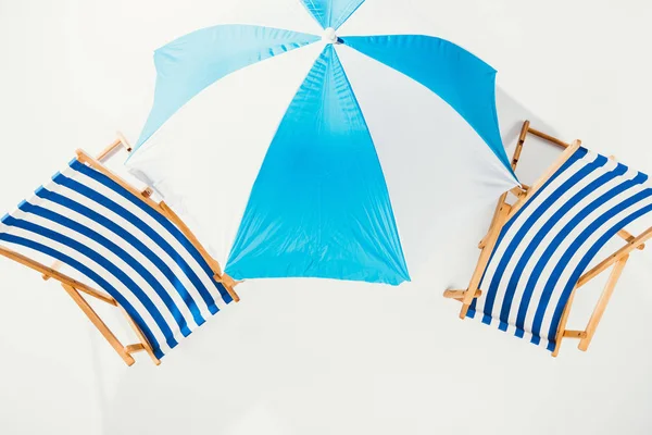 Vista superior de cadeiras de praia listradas e guarda-chuva de praia isolado em branco — Fotografia de Stock