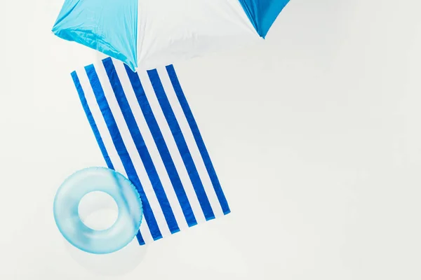 Top view of beach umbrella, striped towel and inflatable ring isolated on white — Stock Photo