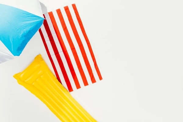 Top view of beach umbrella, striped towel and inflatable mattress isolated on white — Stock Photo