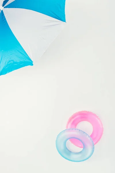 Top view of beach umbrella and inflatable rings isolated on white — Stock Photo