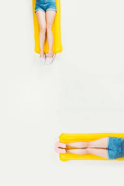 Partial top view of people lying on swimming mattresses isolated on white — Stock Photo