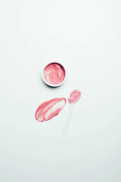 Top view of smudge, spoon and pink mask in container on white surface — Stock Photo