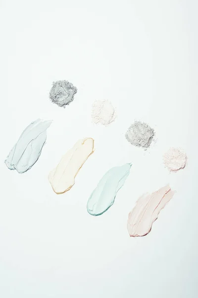 Top view of various clay powder and colorful clay mask smudges placed in row isolated on white surface — Stock Photo