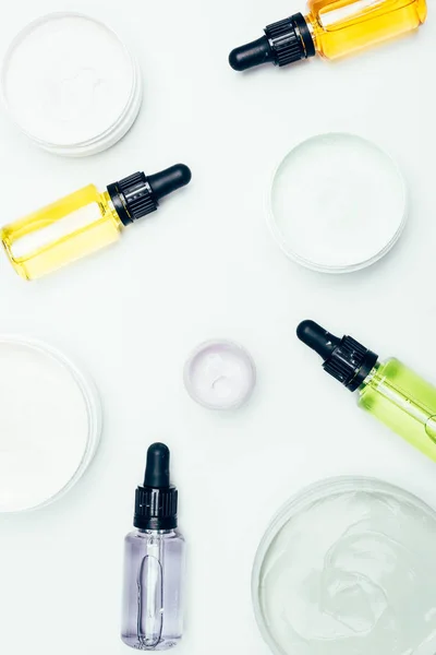 Top view of cosmetic bottles with pipes and containers with clay masks isolated on white surface — Stock Photo