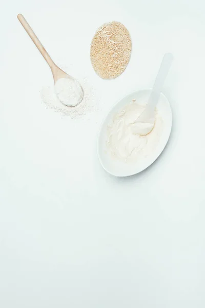 Vista dall'alto di cucchiai, polvere di argilla, spugna e piatto con maschera di argilla isolata su superficie bianca — Foto stock