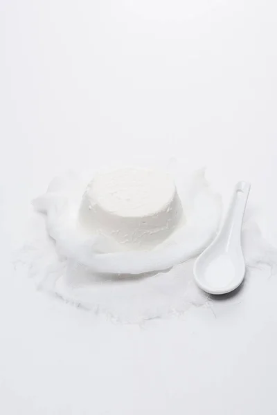 Healthy cottage cheese on cheesecloth on white surface — Stock Photo