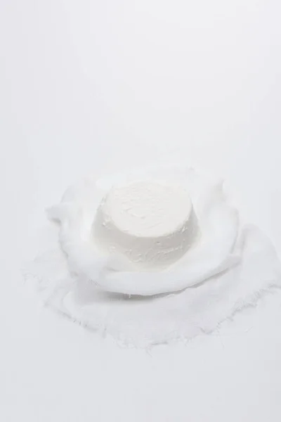 Creamy cottage cheese on cheesecloth on white surface — Stock Photo