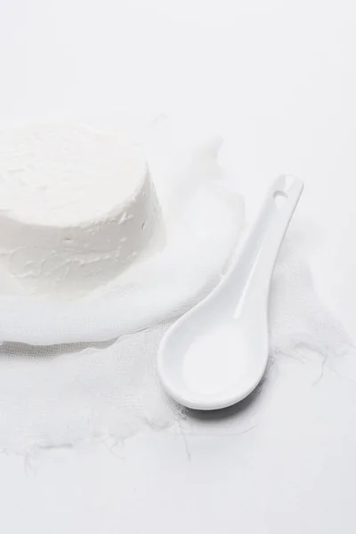 Delicious cottage cheese on cheesecloth with spoon on white tabletop — Stock Photo