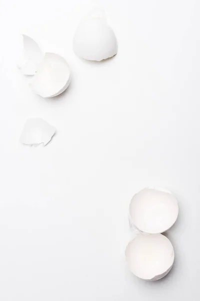 Top view of broken chicken egg shells on white surface — Stock Photo