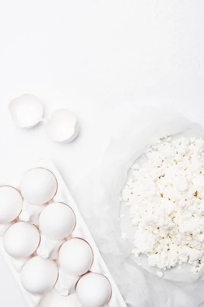 Vista dall'alto di fiocchi di latte fatti in casa e uova sulla superficie bianca — Foto stock